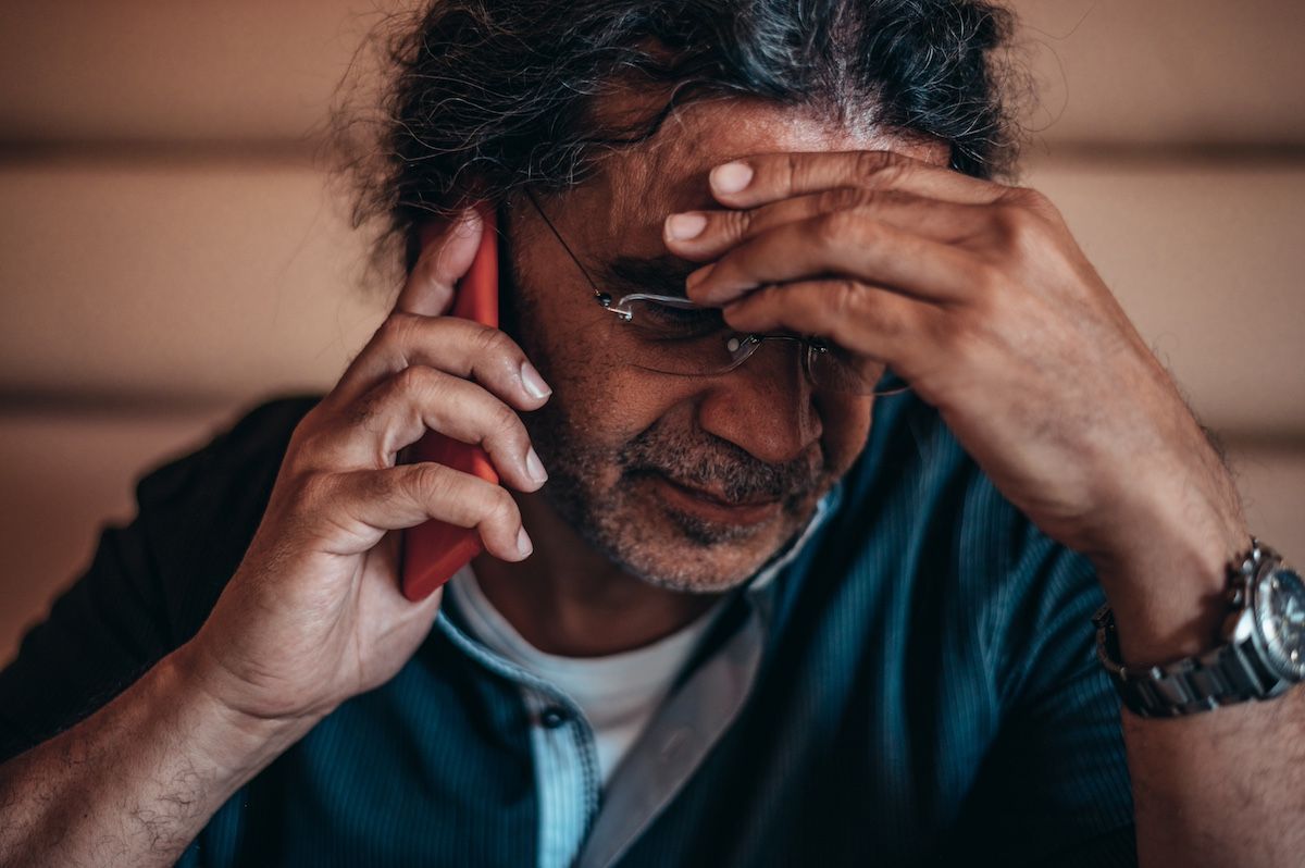 a man looks frustrated while talking to someone on his cell phone.