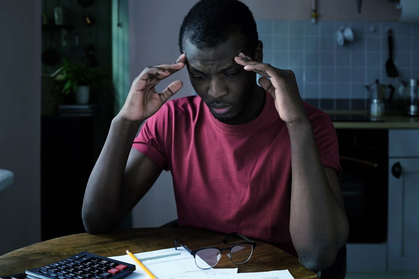 A man sits at his kitchen table stressed out over bills from a personal injury.
