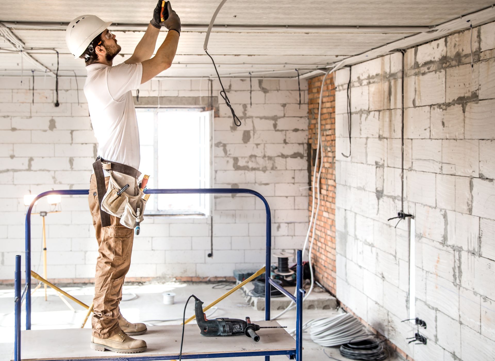 A man is standing on a scaffolding working on a ceiling.