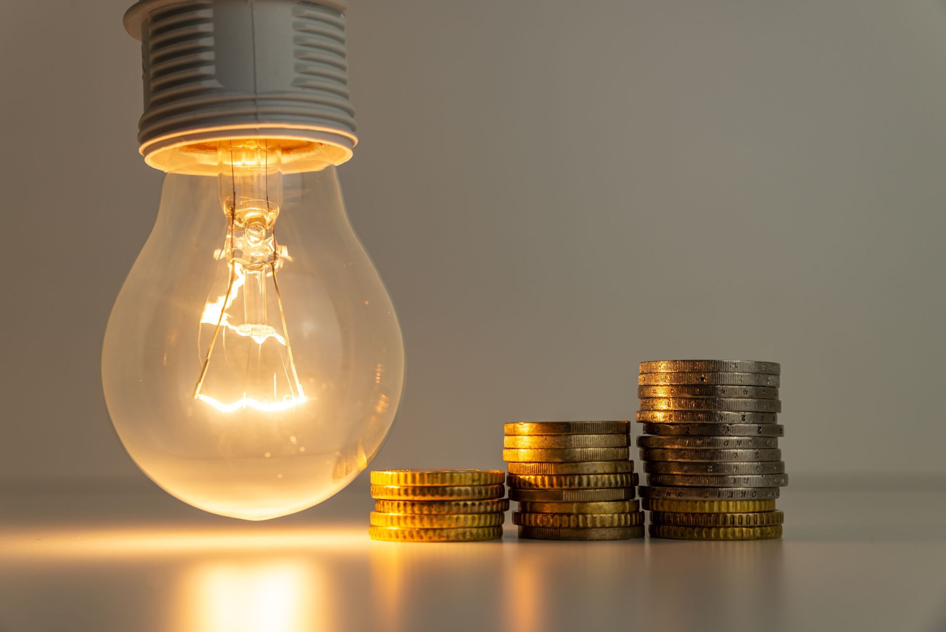 A light bulb is sitting next to stacks of coins on a table.