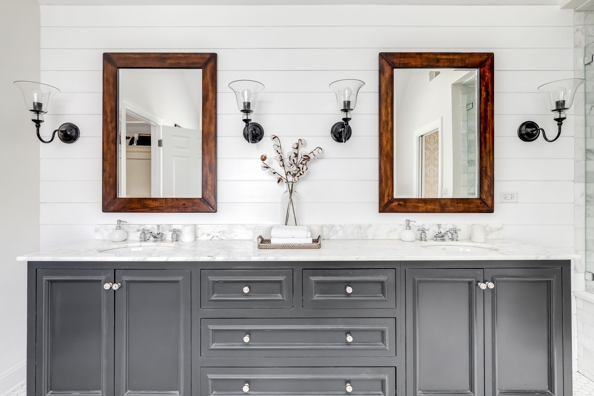 Bathroom vanity with two mirrors, dark gray cabinets, and white countertop.