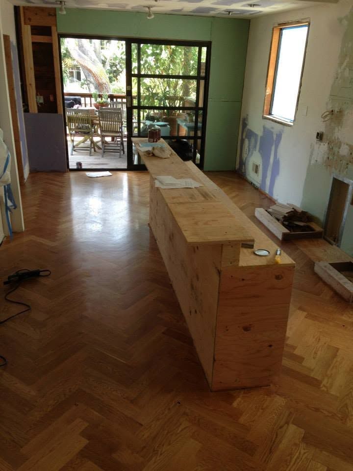 Light wood kitchen with island, cabinets, shelves, and window seat.