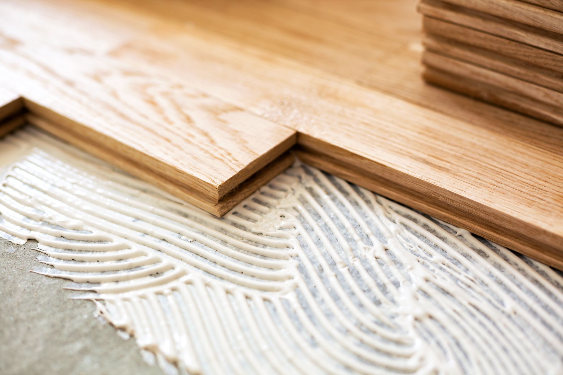 Wooden planks being glued and laid on a floor, close-up view.