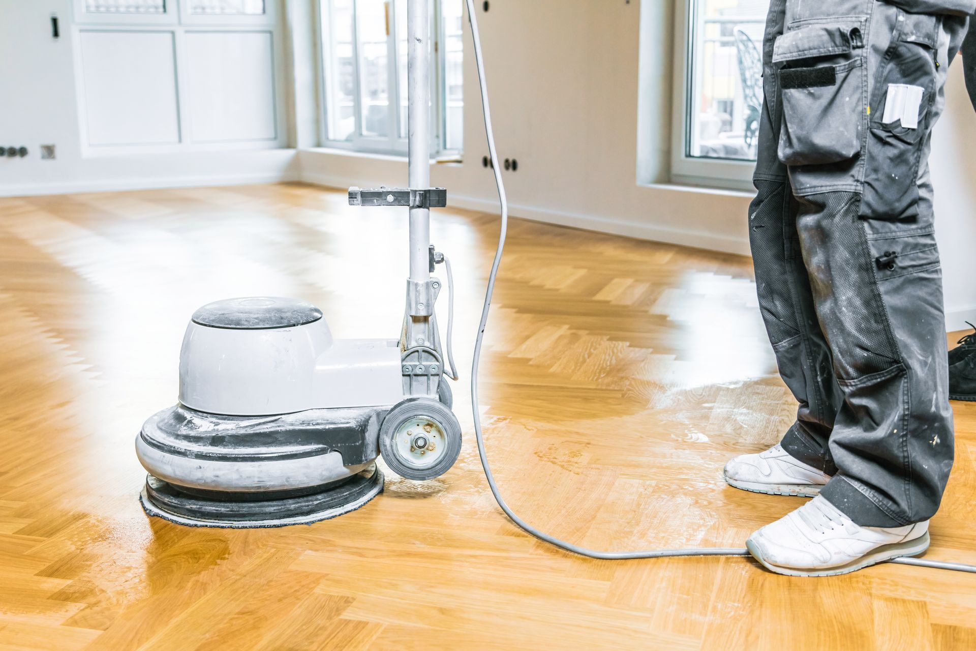 Man using a floor polishing machine on a light wood floor.