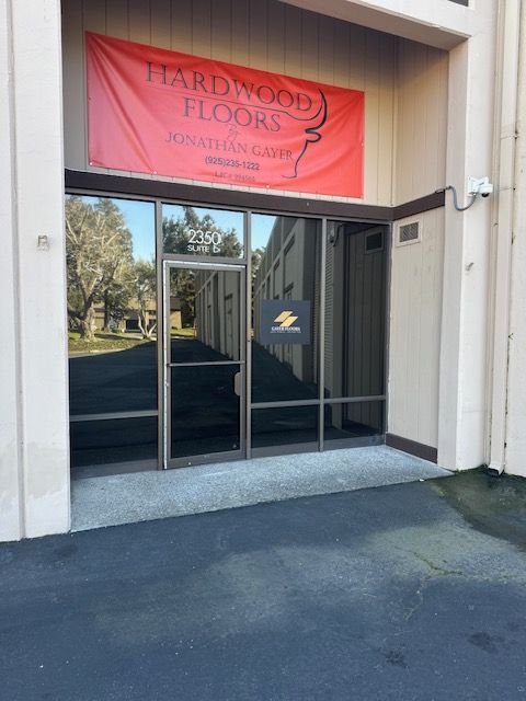 Storefront entrance with red banner for “Hardwood Floors” and glass double doors