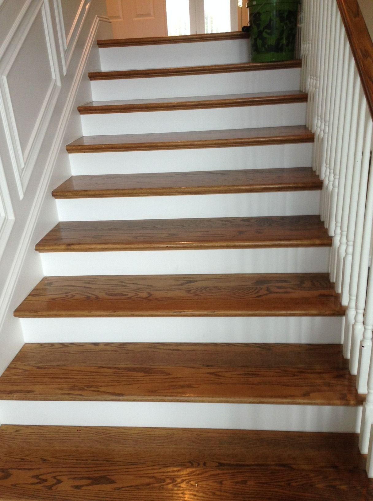 Wooden stairs with white risers and handrail, leading upwards.