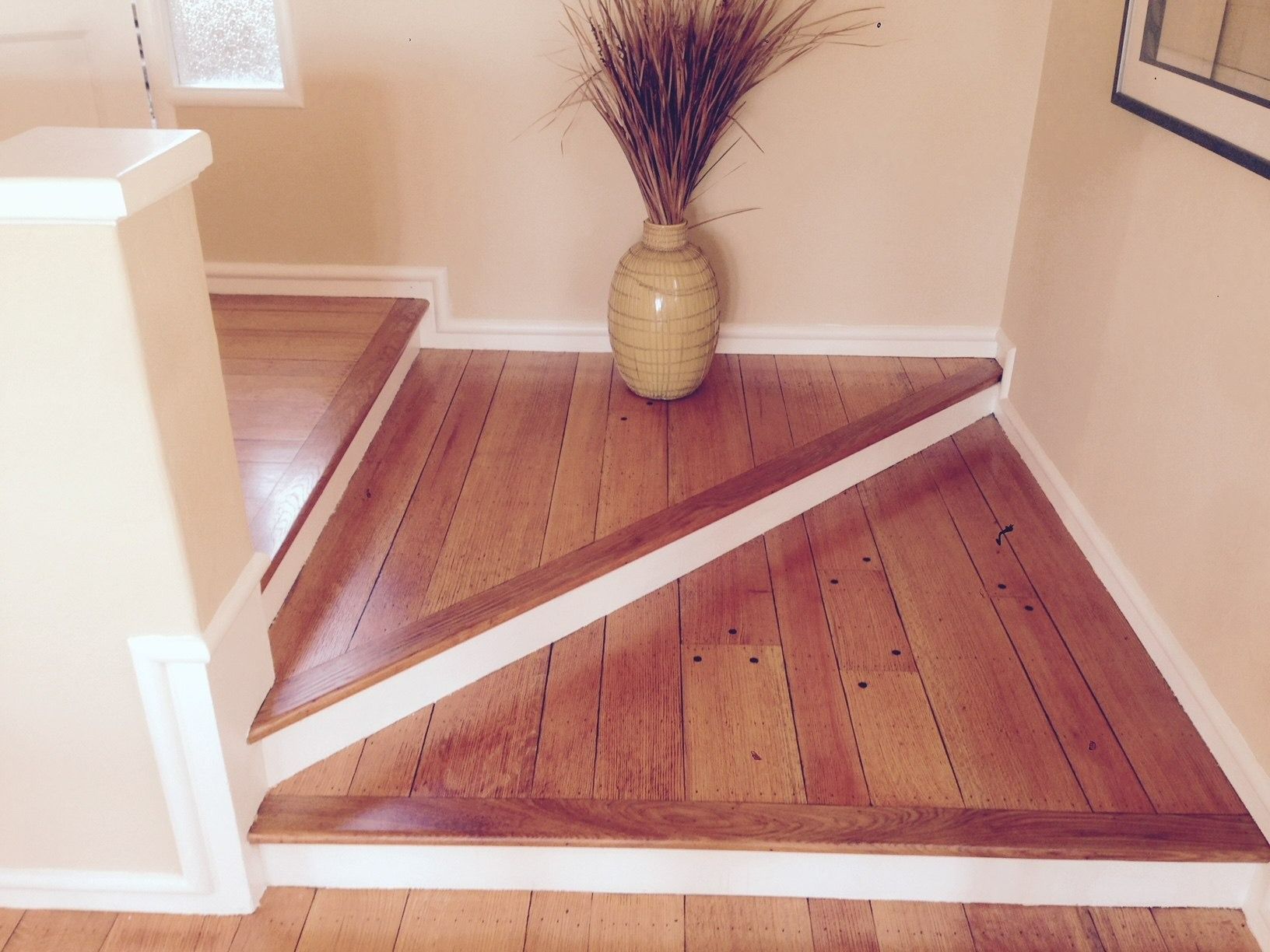 Wooden flooring with a diagonal design and decorative vase.