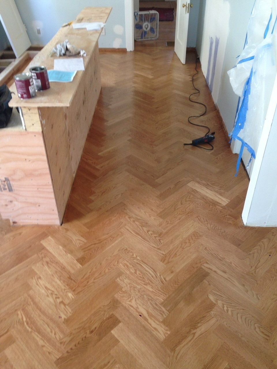 Herringbone wood floor, adjacent to a light-colored wood counter; room is under renovation.