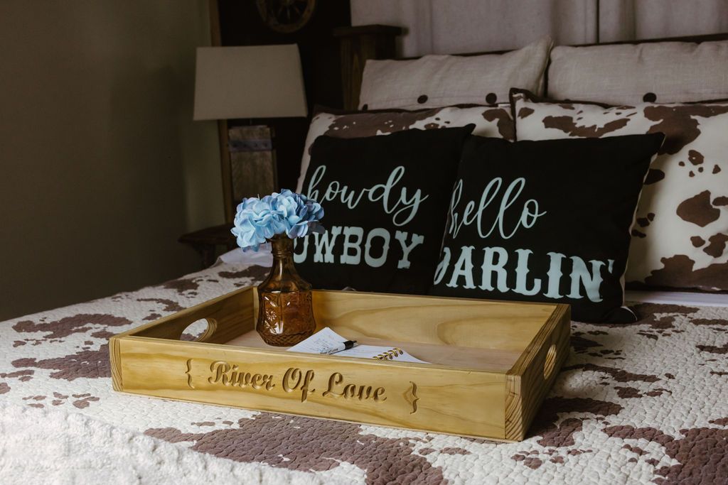 Rustic bedroom tray on a bed with blue flowers and a black pillow reading “hello marlin”