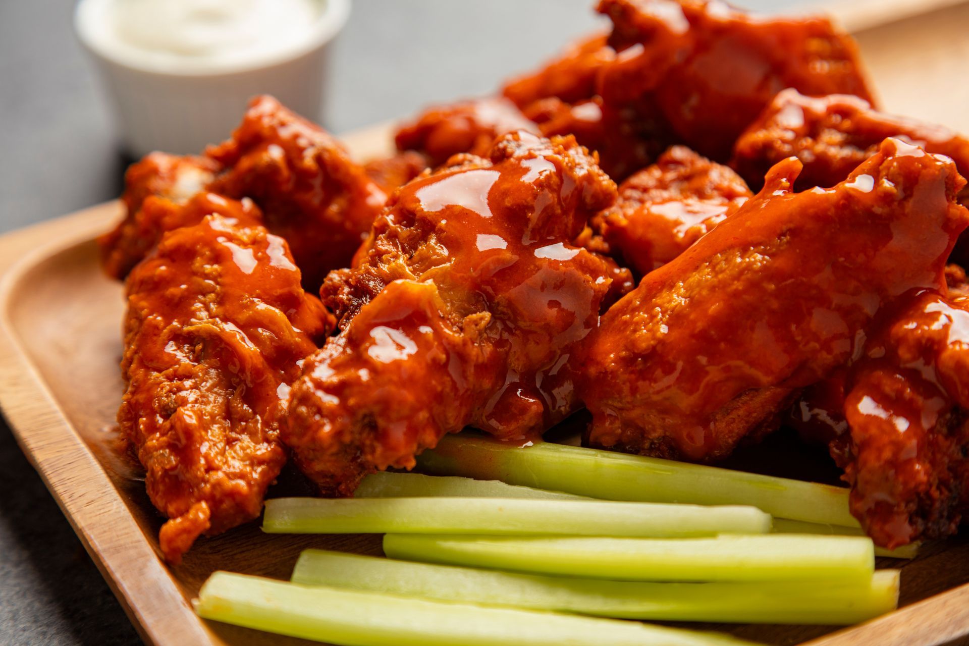 Buffalo chicken wings with celery sticks and dipping sauce on a tray