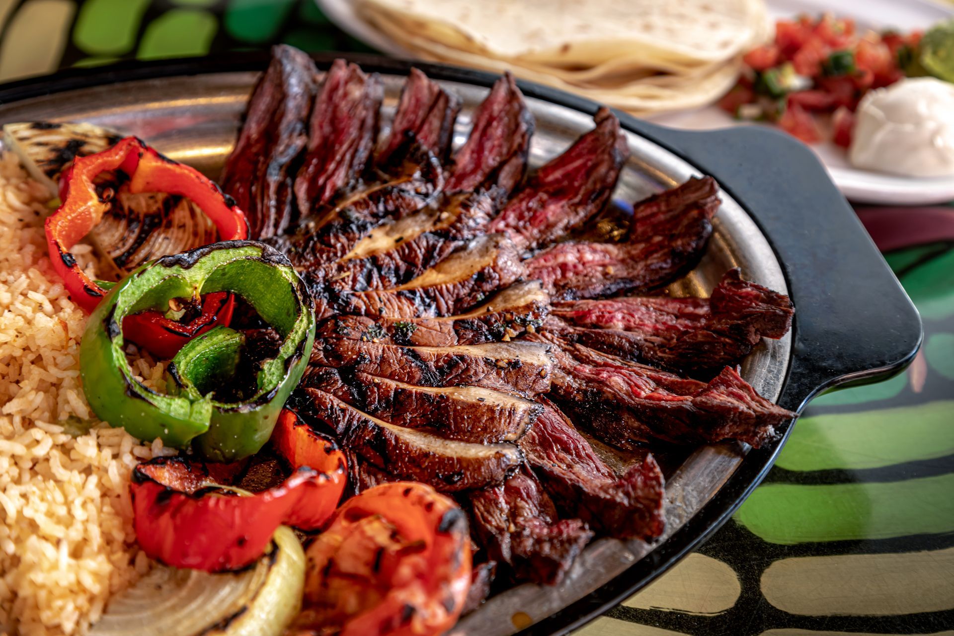 Grilled meat platter with roasted vegetables, pita bread, and rice on a serving tray
