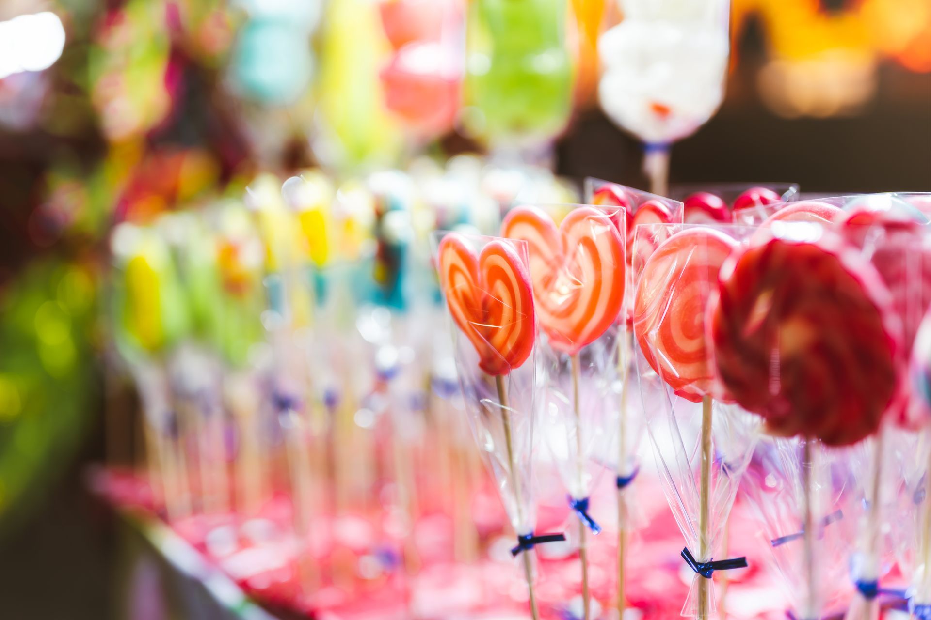 Colorful lollipops in clear wrappers displayed in rows at a candy shop