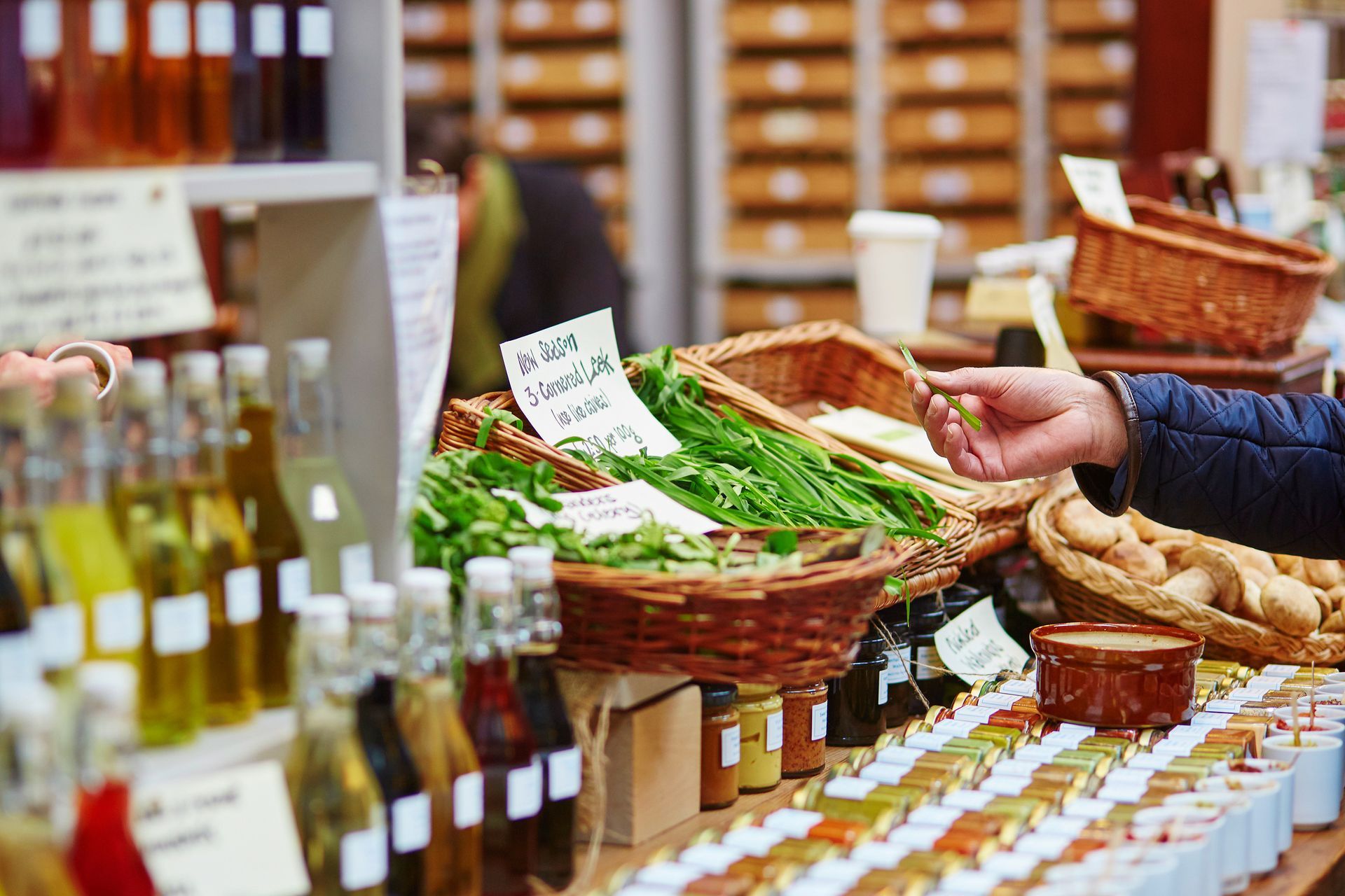 Market stall with baskets of fresh produce, bread, and bottles on display