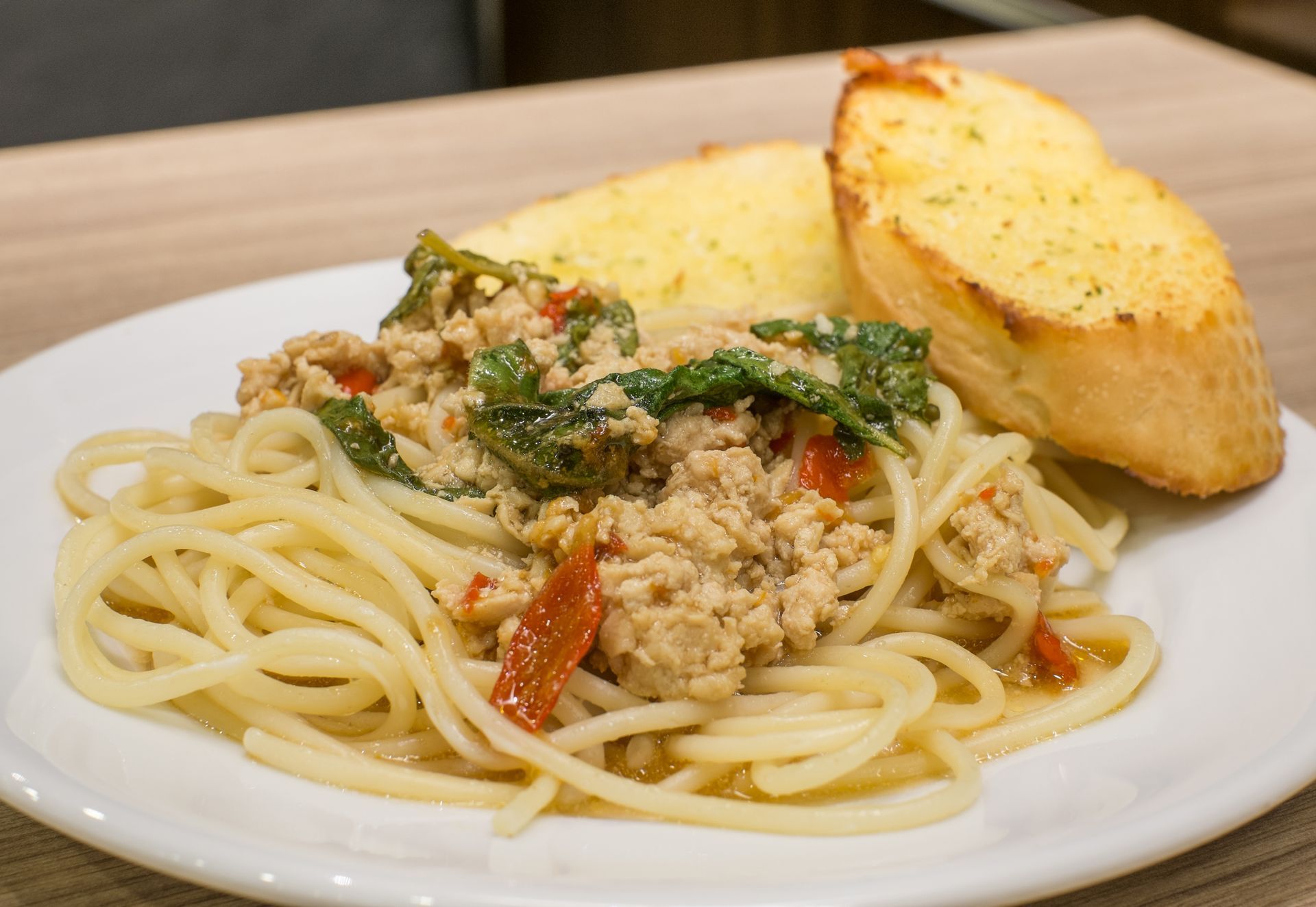 Plate of spaghetti with meat sauce and bread slices on a white dish