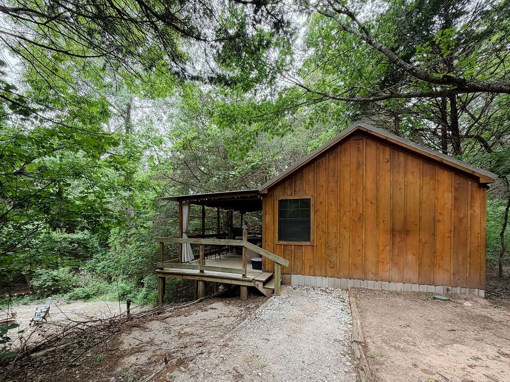 Small wooden cabin with porch in a wooded forest clearing