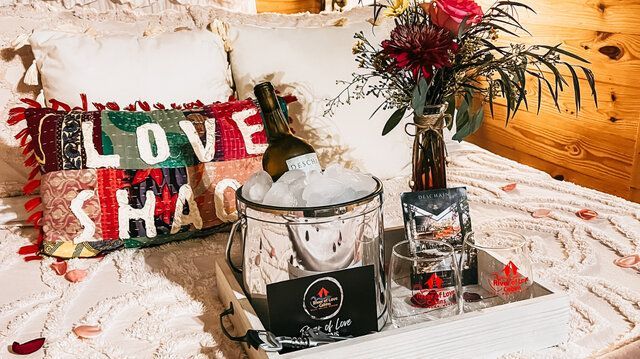 Holiday decor with red-and-green LOVE sign, wrapped gift, candles, and floral arrangement on a white table