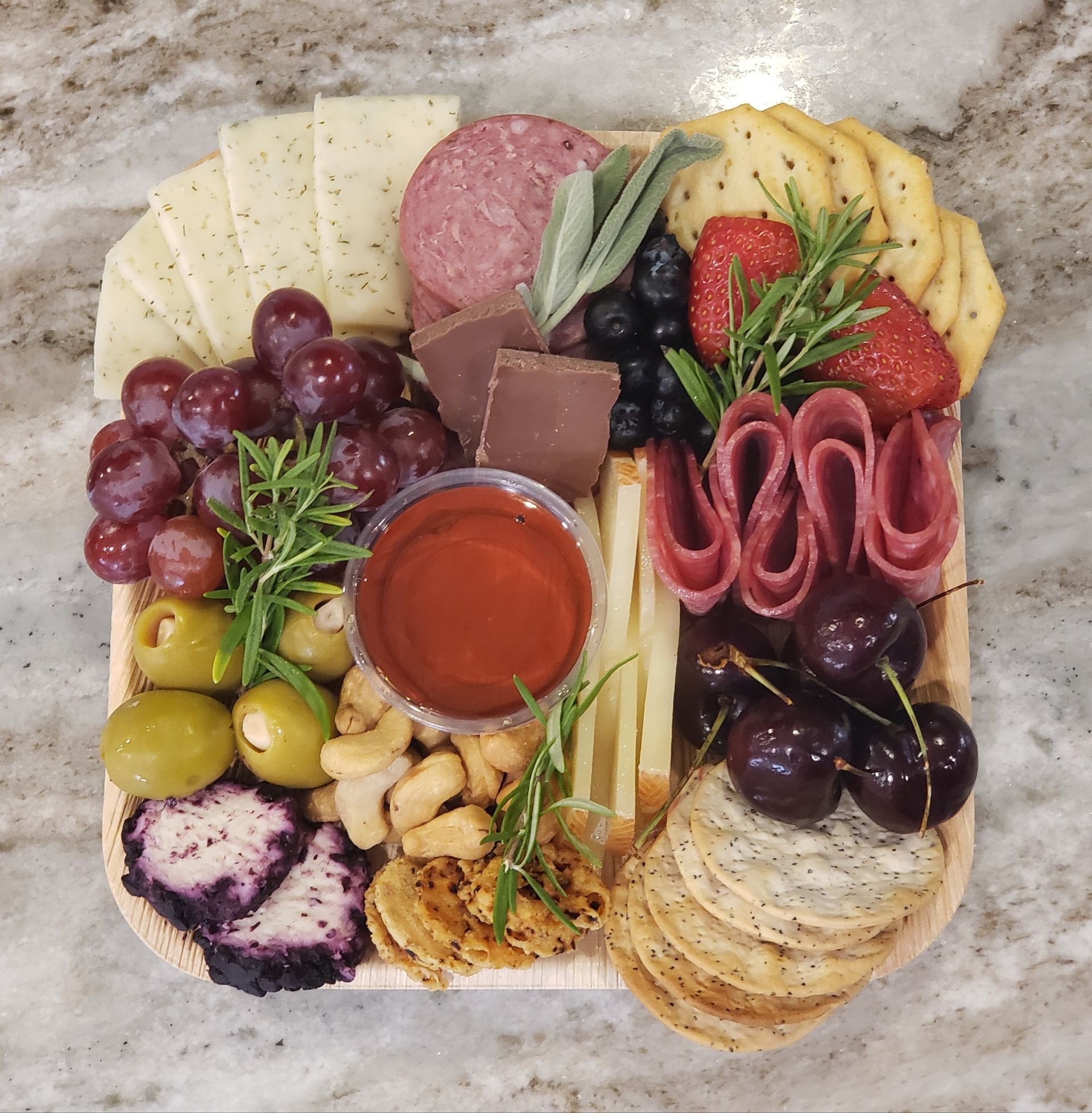 Charcuterie board with cheeses, meats, grapes, berries, olives, crackers, nuts, and dip