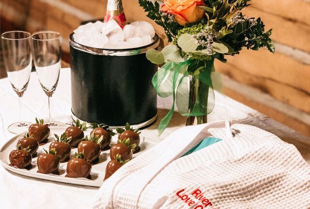 Champagne and chocolate-covered strawberries on a table with flowers and white napkins