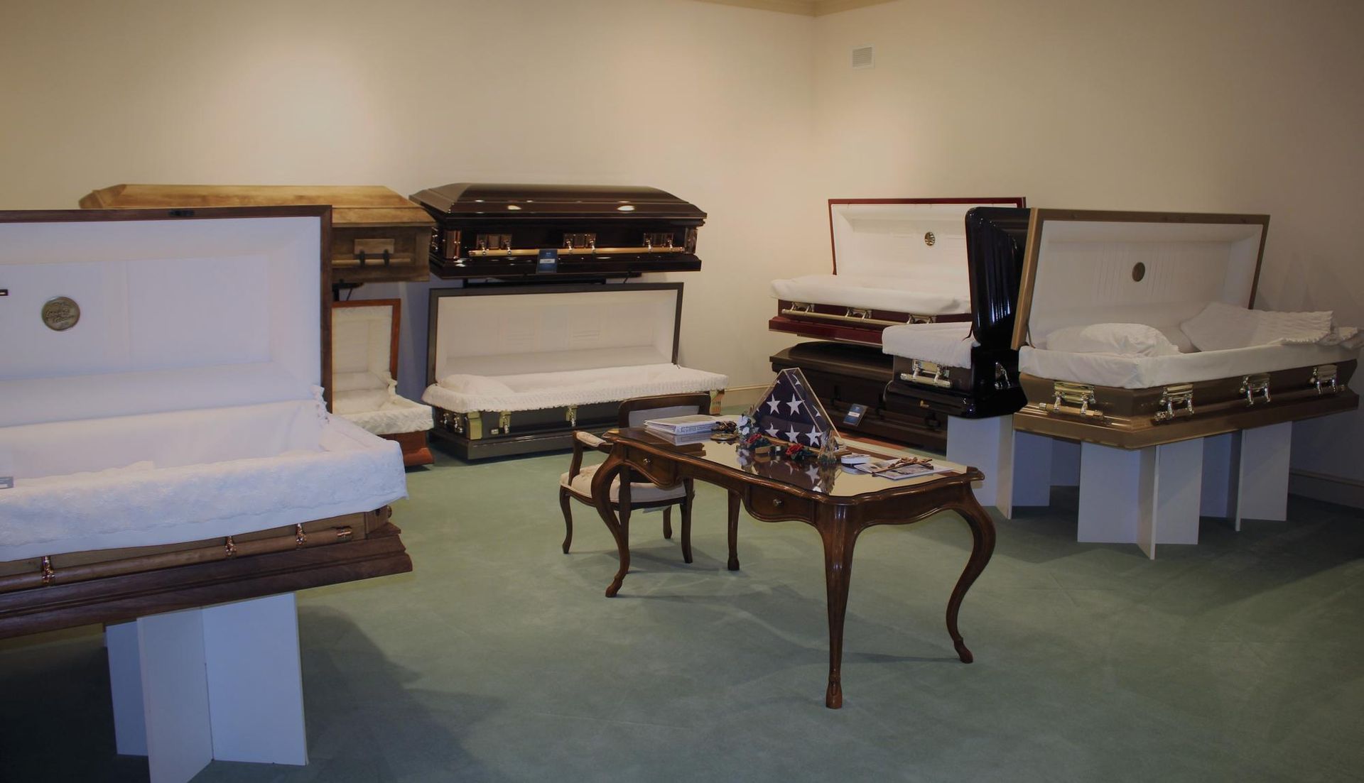 Display of antique pianos and harpsichords in a museum room with pale walls and carpet