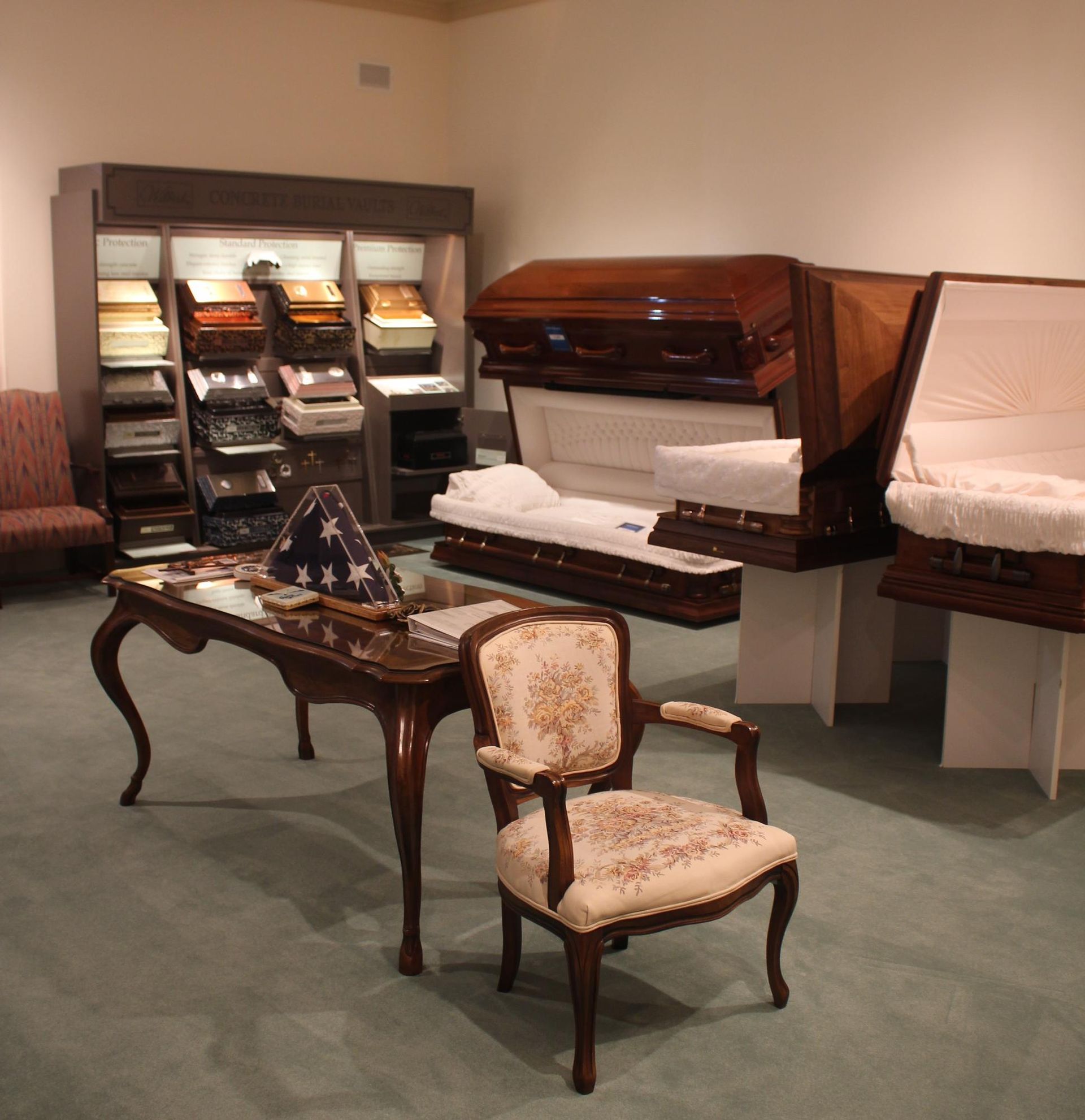Exhibit room with antique furniture and a white-blanketed casket displayed on the right.