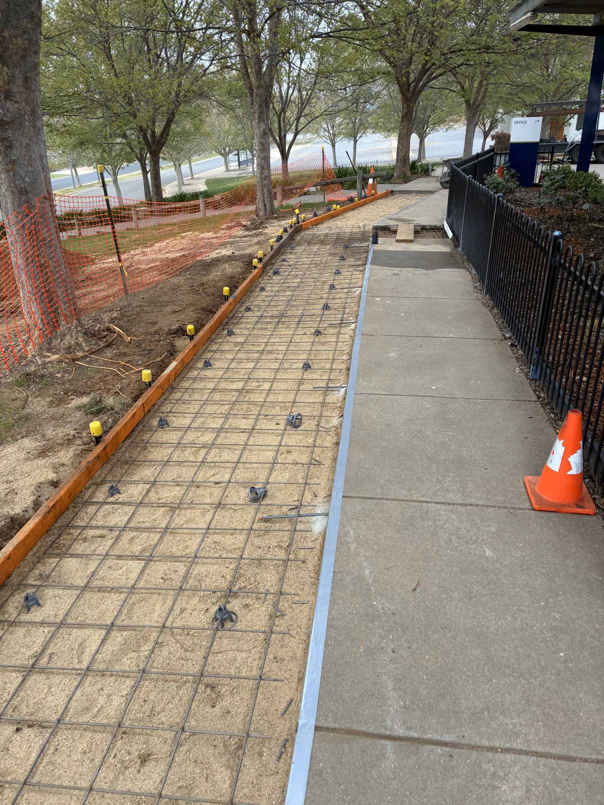 New walkway under construction beside a fenced sidewalk, with trees and orange cones along the path — Complete Concreting Riverina In Ashmont, NSW