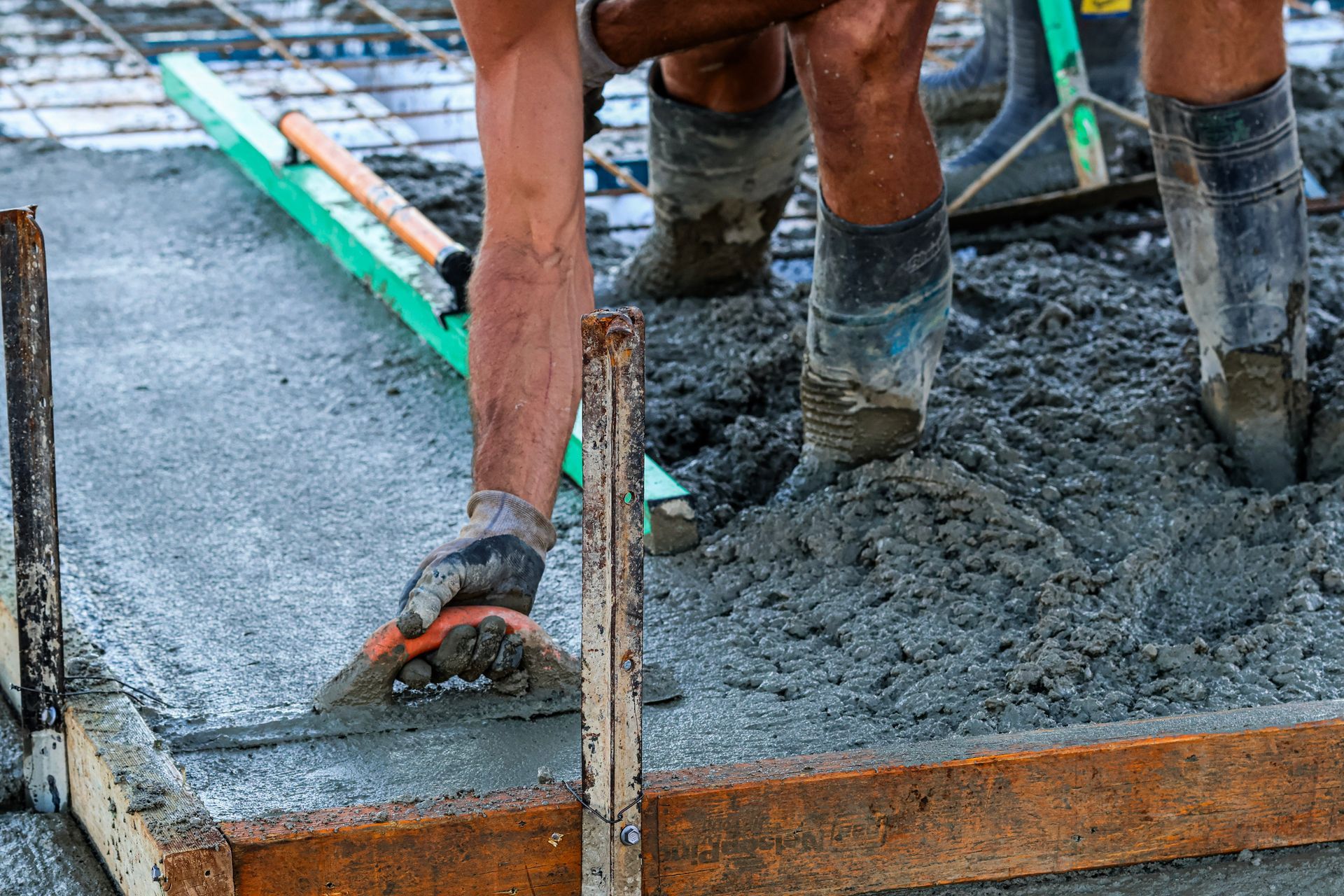 Workers pouring wet concrete into a form at a construction site — Complete Concreting Riverina In Ashmont, NSW