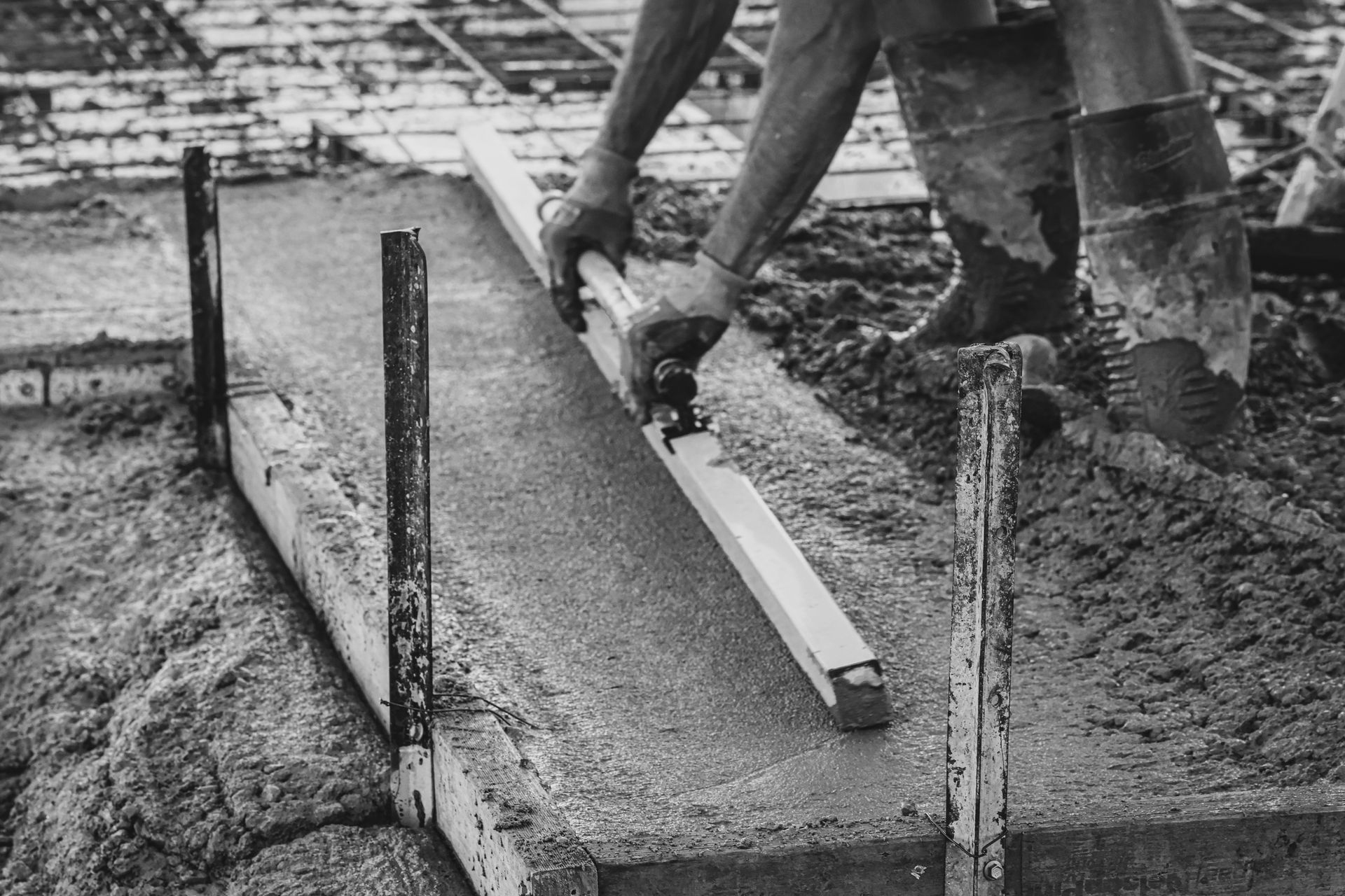 Worker smoothing wet concrete with a straightedge at a construction site. — Complete Concreting Riverina In Ashmont, NSW
