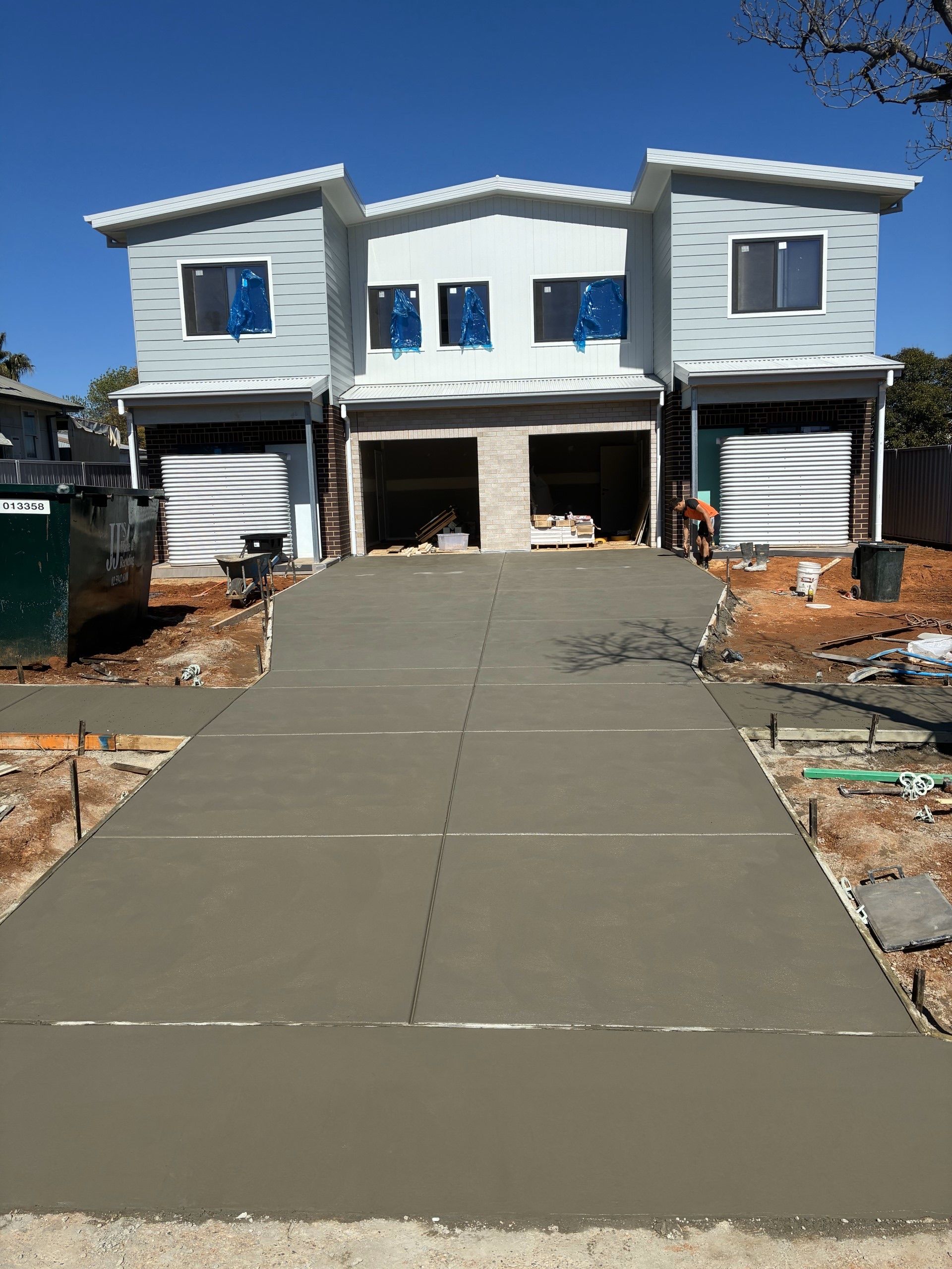 New two-story house under construction with a freshly poured concrete driveway leading to the garage — Complete Concreting Riverina In Ashmont, NSW