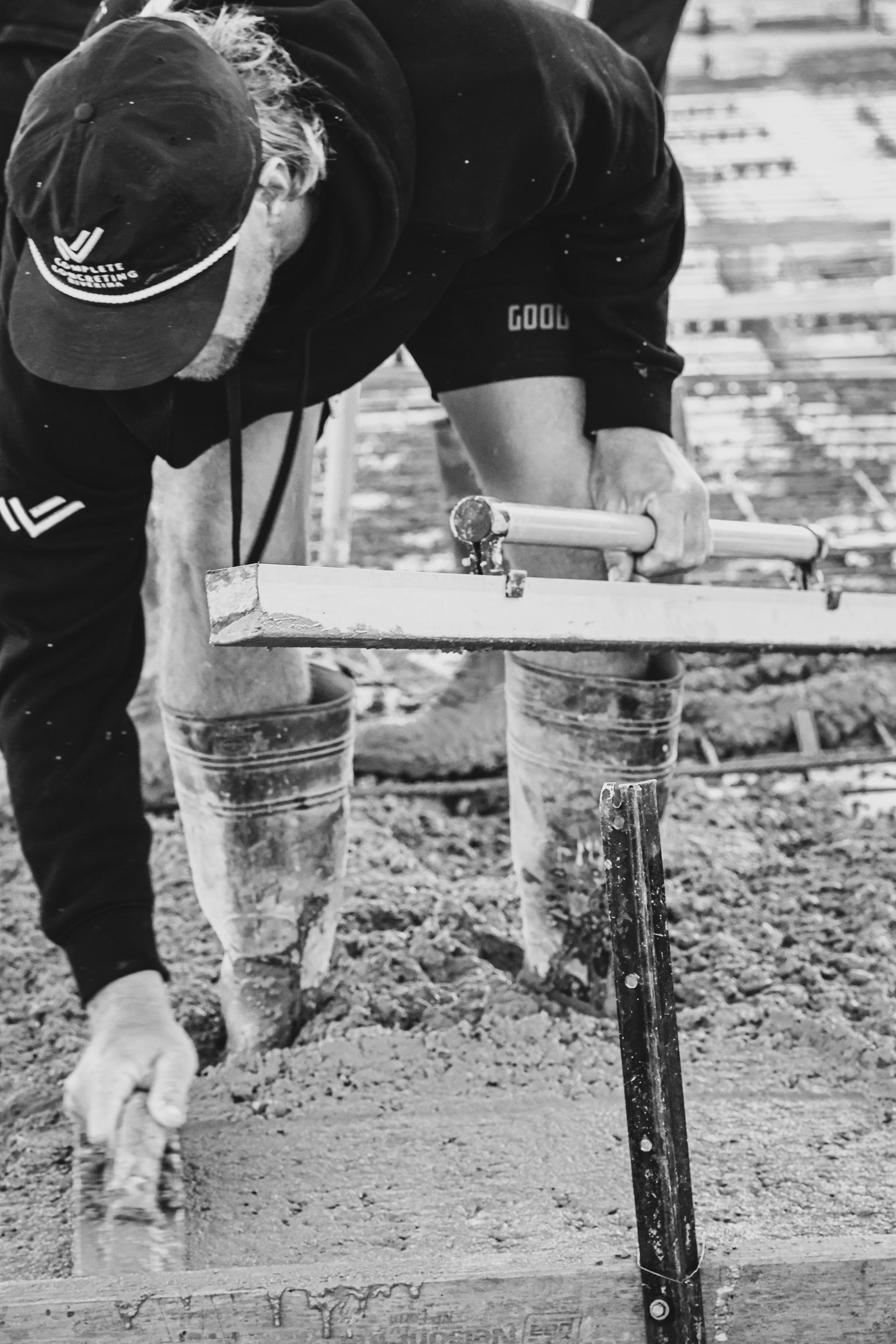 Worker smoothing wet concrete beside wooden formwork at a construction site — Complete Concreting Riverina In Ashmont, NSW