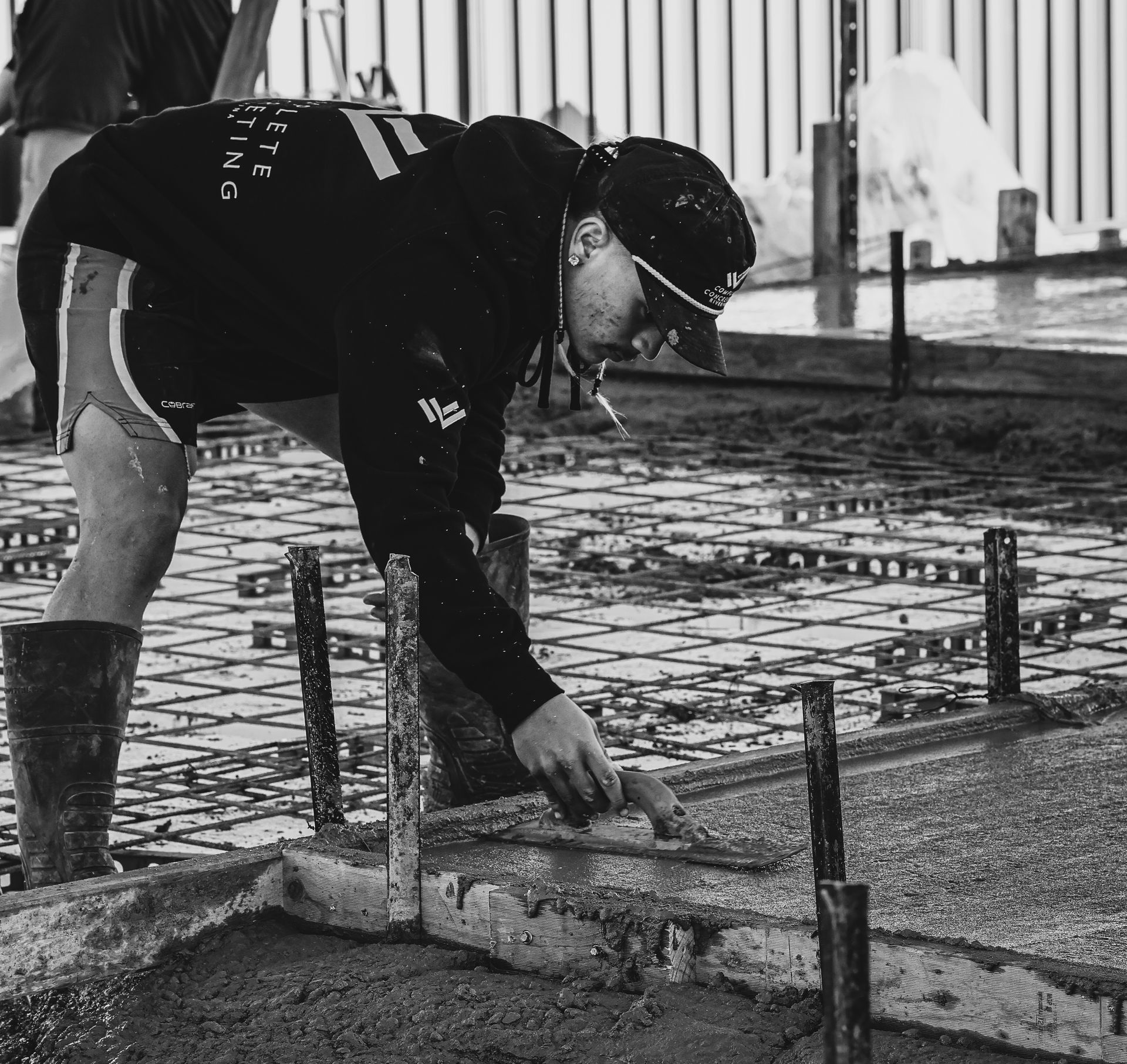 Worker smoothing wet concrete around rebar at a construction site — Complete Concreting Riverina In Ashmont, NSW