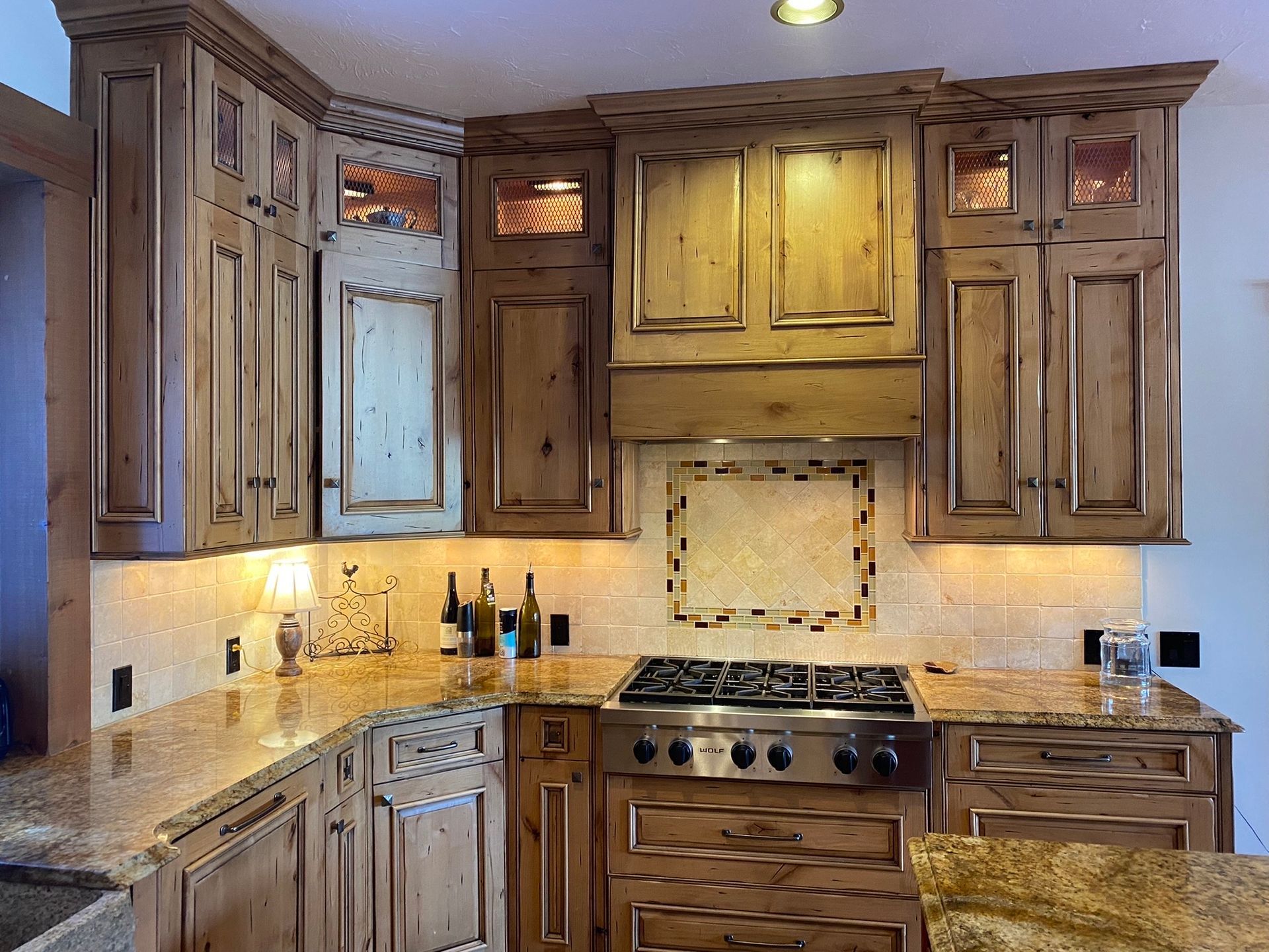 Rustic kitchen with wood cabinets, granite countertops, a tiled backsplash, and a stainless steel gas stove.