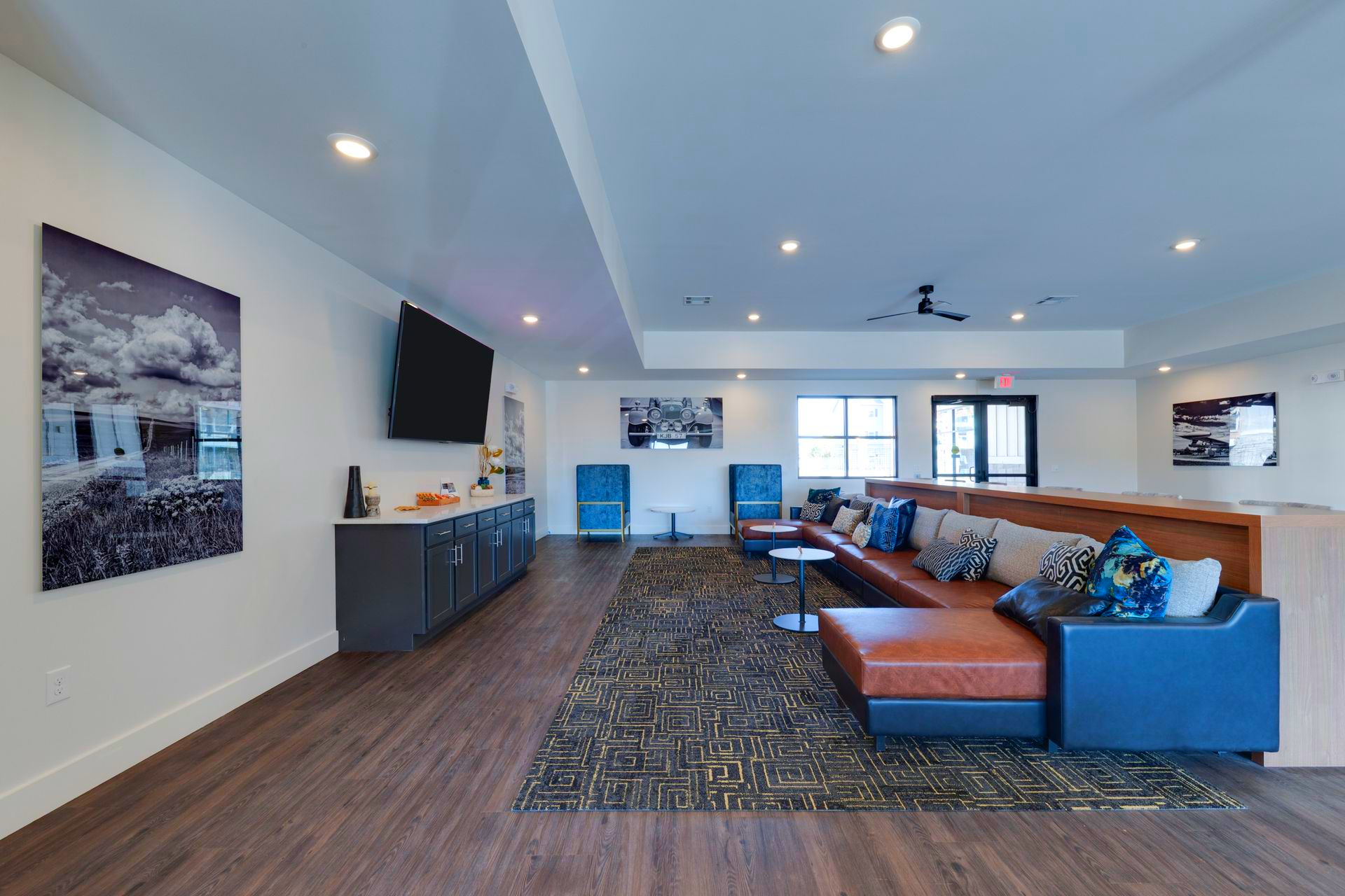 Modern lounge with sectional sofa, TV, art, and dark wood flooring.