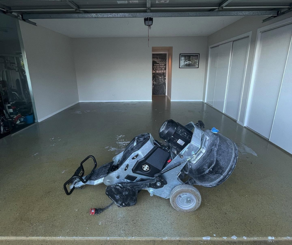 Garage with a toppled black and gray stroller or baby carrier on the wet floor. Garage with a toppled black and gray stroller or baby carrier on the wet floor.