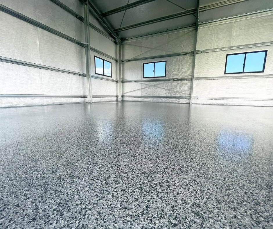 Empty industrial warehouse with polished speckled floor and high windows letting in daylight