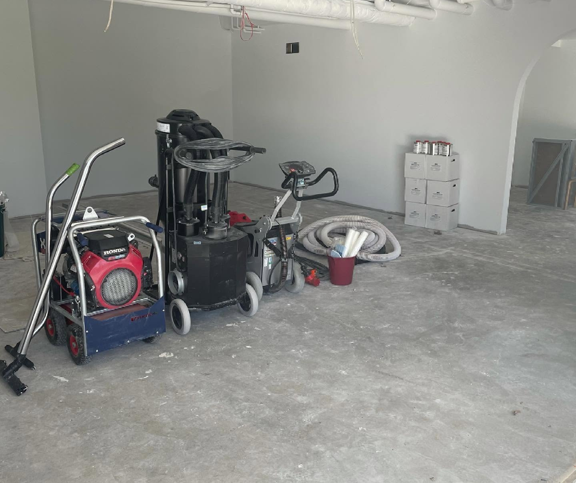 Garage with construction equipment, cords, and tools on a dusty concrete floor.