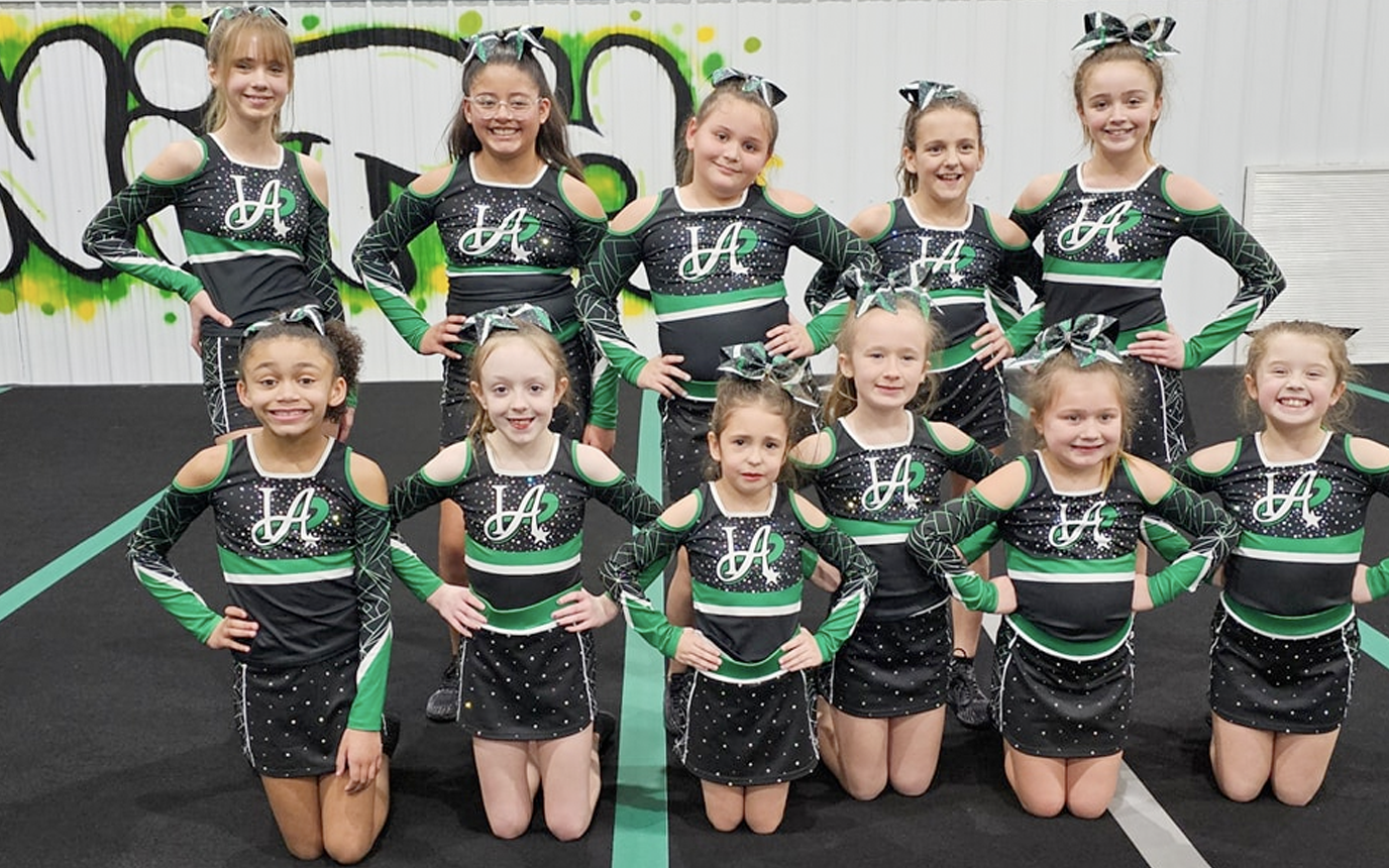 A group of cheerleaders are posing for a picture.