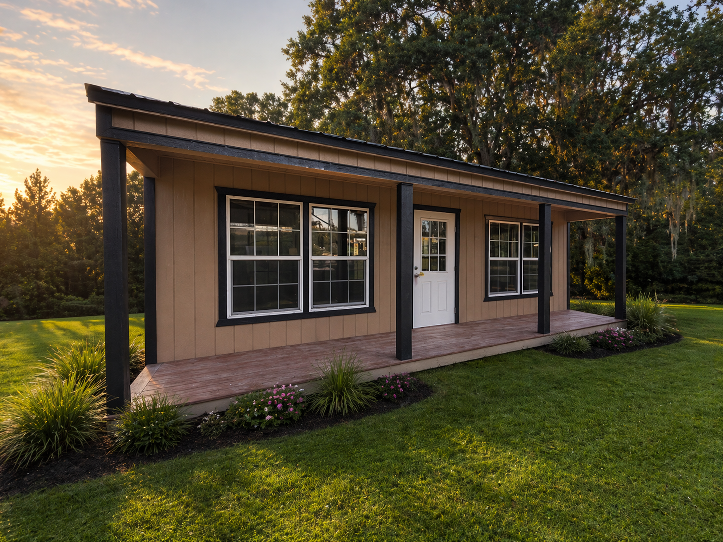 Row of colorful cabins with porches, nestled near a wooded area with green grass and a gravel path.