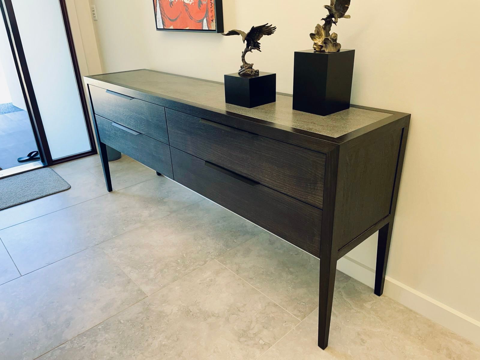 Dark Wood Sideboard With Two Sets of Drawers, Topped With Sculptures, in a Well-lit Hallway — Norrland in Warners Bay, NSW