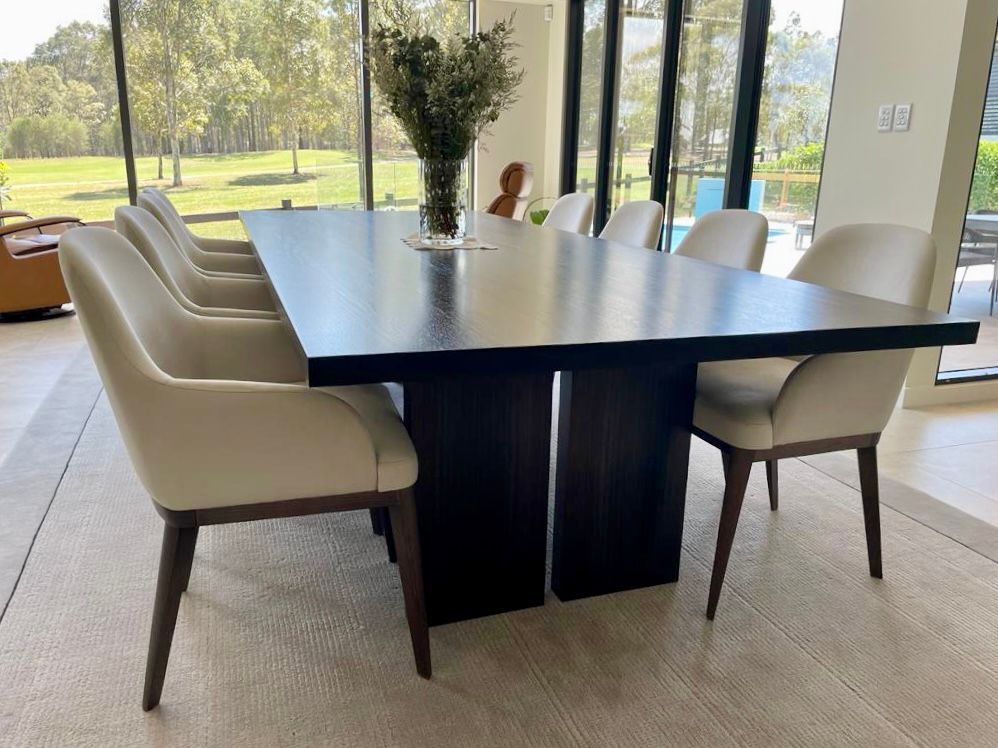 Dark Wood Dining Table With Eight Beige Chairs, a Vase of Flowers, and a Scenic Outdoor View — Norrland in Warners Bay, NSW