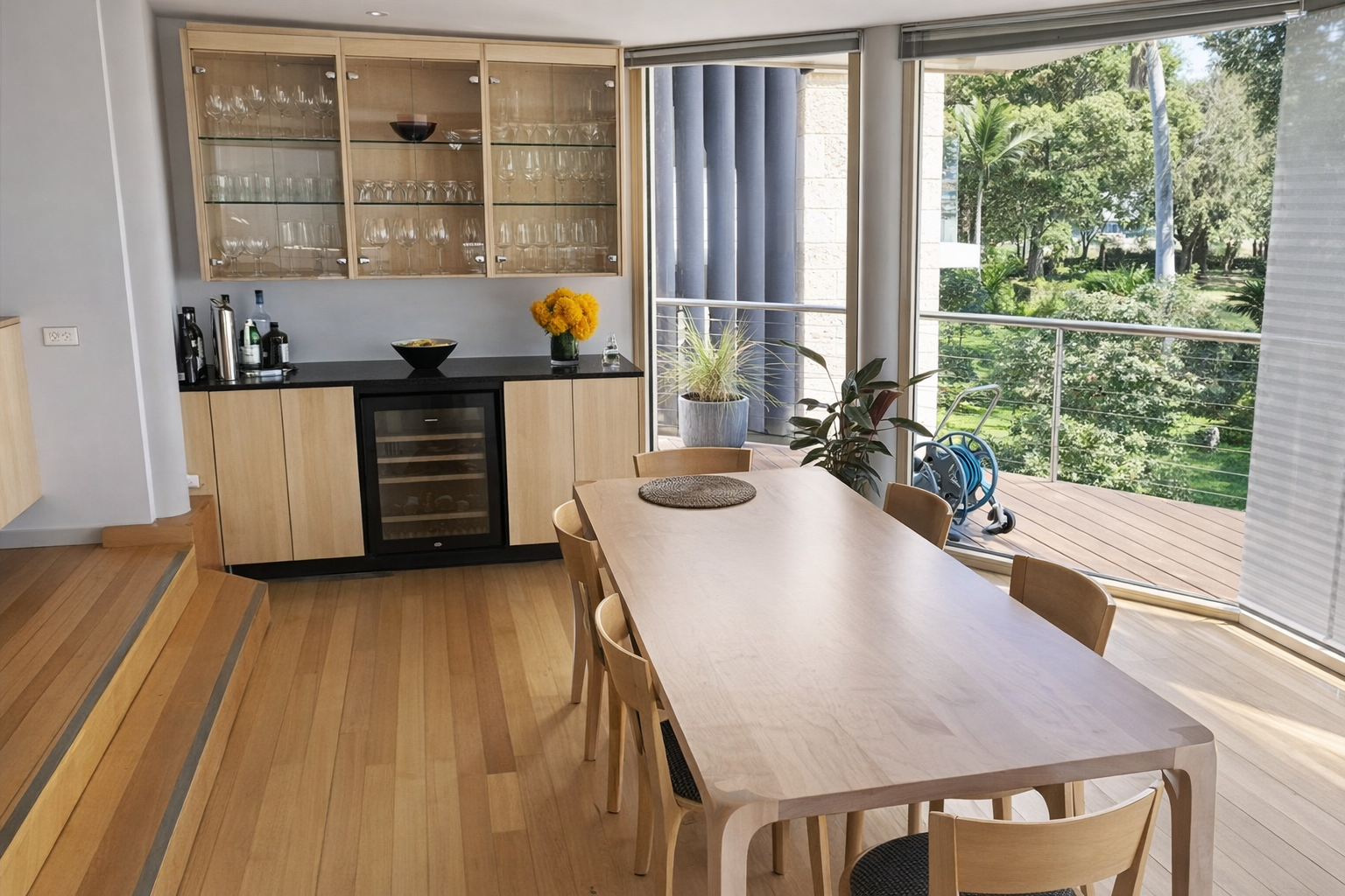 A light wood dining table with chairs sits next to a home bar with cabinets — Norrland in Warners Bay, NSW