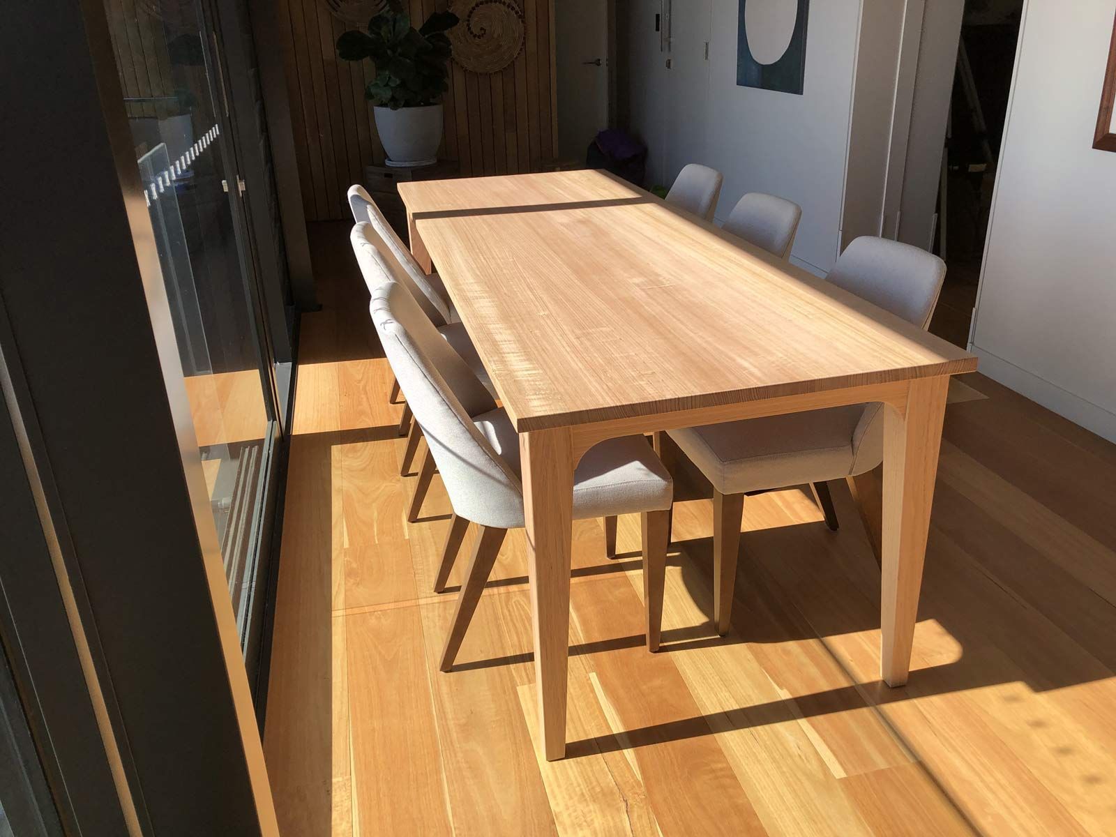 Wooden Dining Table With Eight Upholstered Chairs in a Sunny Room — Norrland in Warners Bay, NSW