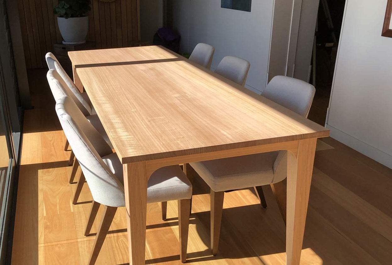 A light wood dining table with six upholstered chairs in a sunlit room with hardwood floors — Norrland in Warners Bay, NSW