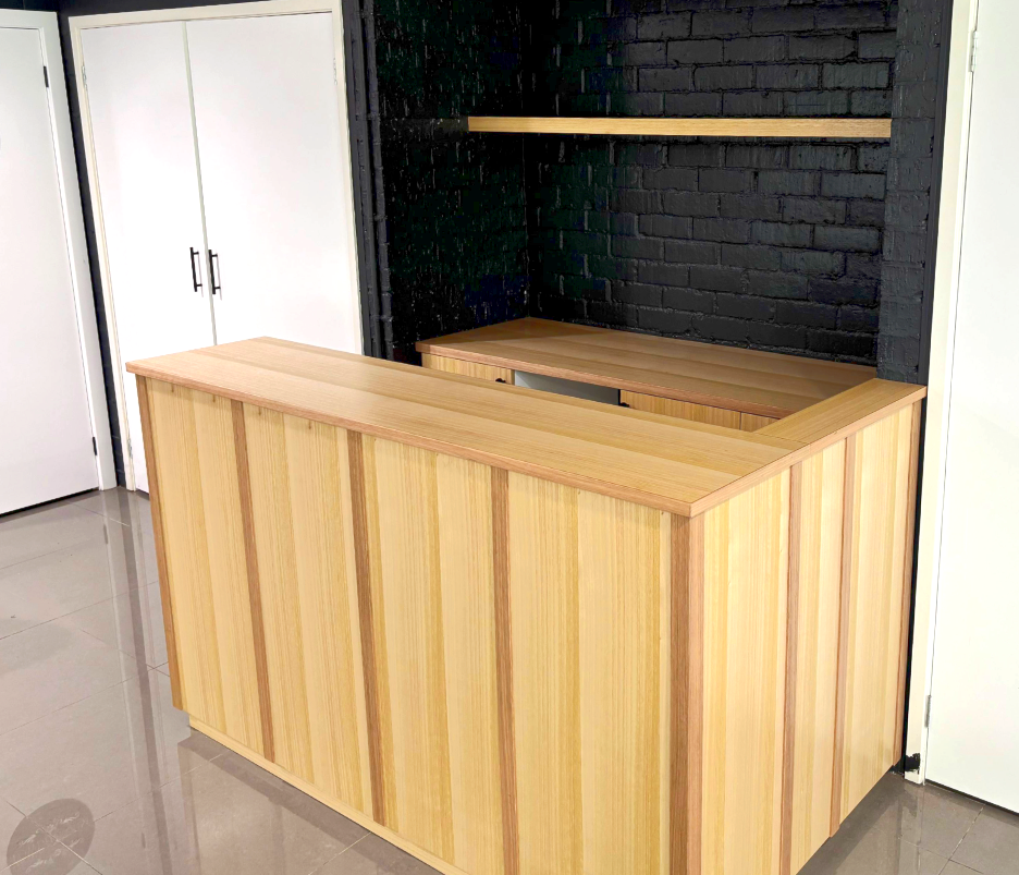 Wooden reception counter in a modern room with black brick wall and white cabinets