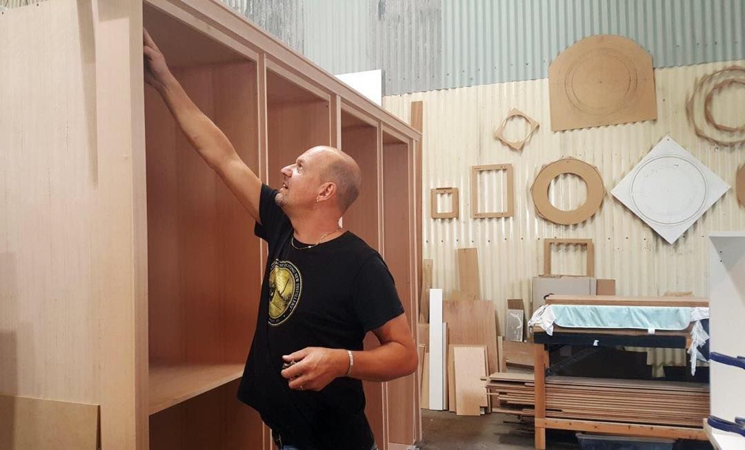 Man in a Workshop Inspecting a Partially Built Wooden Cabinet — Norrland in Warners Bay, NSW