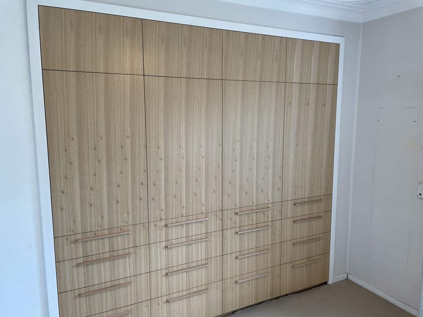 Wooden Wardrobe With Drawers and Upper Cabinets, Set Within a White-framed Recess — Norrland in Warners Bay, NSW