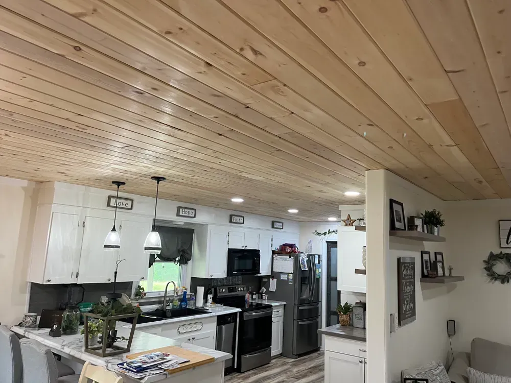 A modern kitchen with off-white cabinetry, black countertops, a black sink, and built-in oven with under-cabinet lighting.