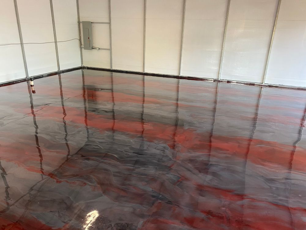 A shiny, marbled epoxy floor with swirling patterns of deep red and black inside a room with white paneled walls.