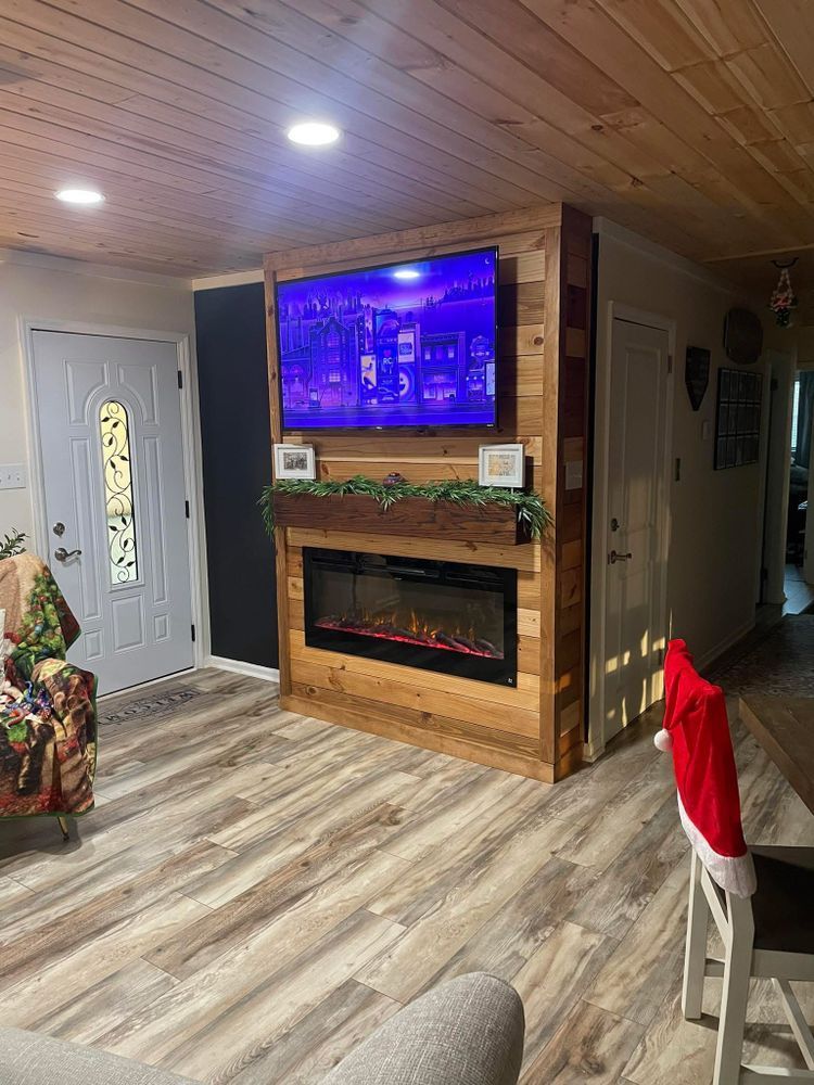 A living room with a wood-paneled feature wall, an electric fireplace, a wall-mounted TV, and light wood-grain flooring.