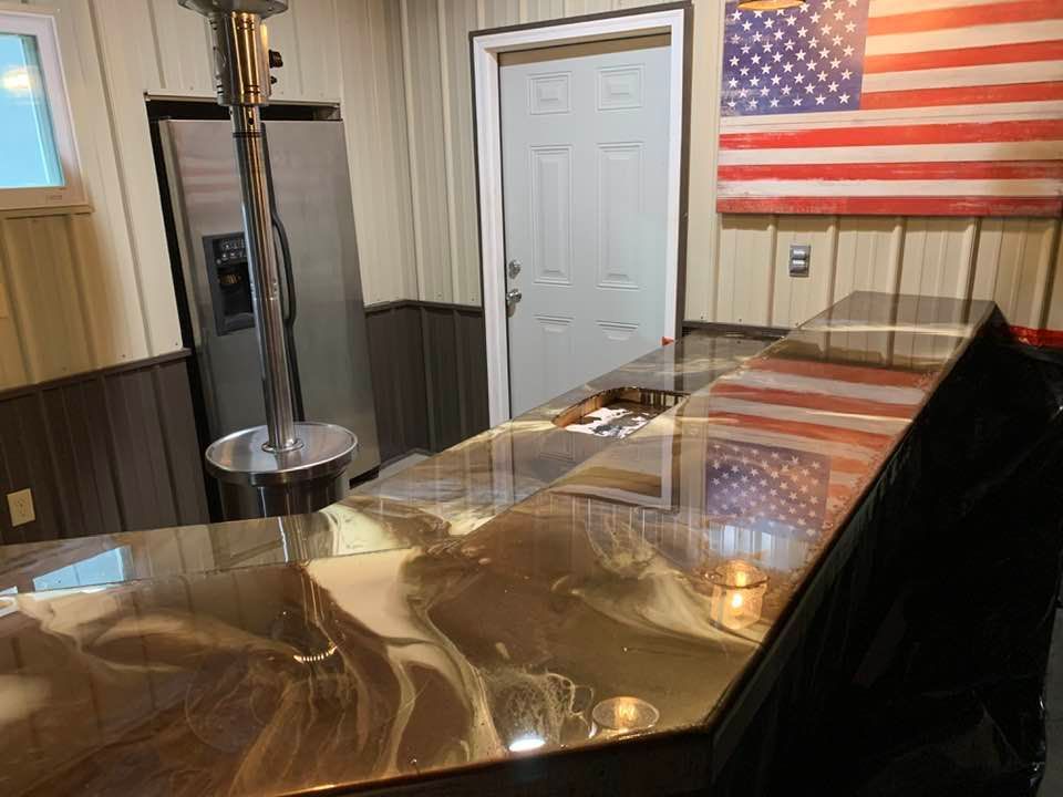 A polished brown, marbled epoxy bar top with metallic highlights in a room featuring an American flag wall hanging.