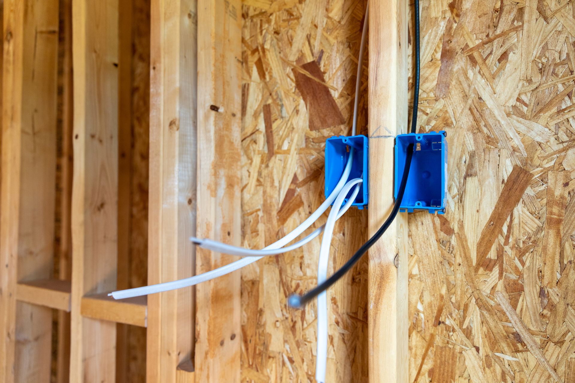 A wooden wall with electrical wires coming out of it.